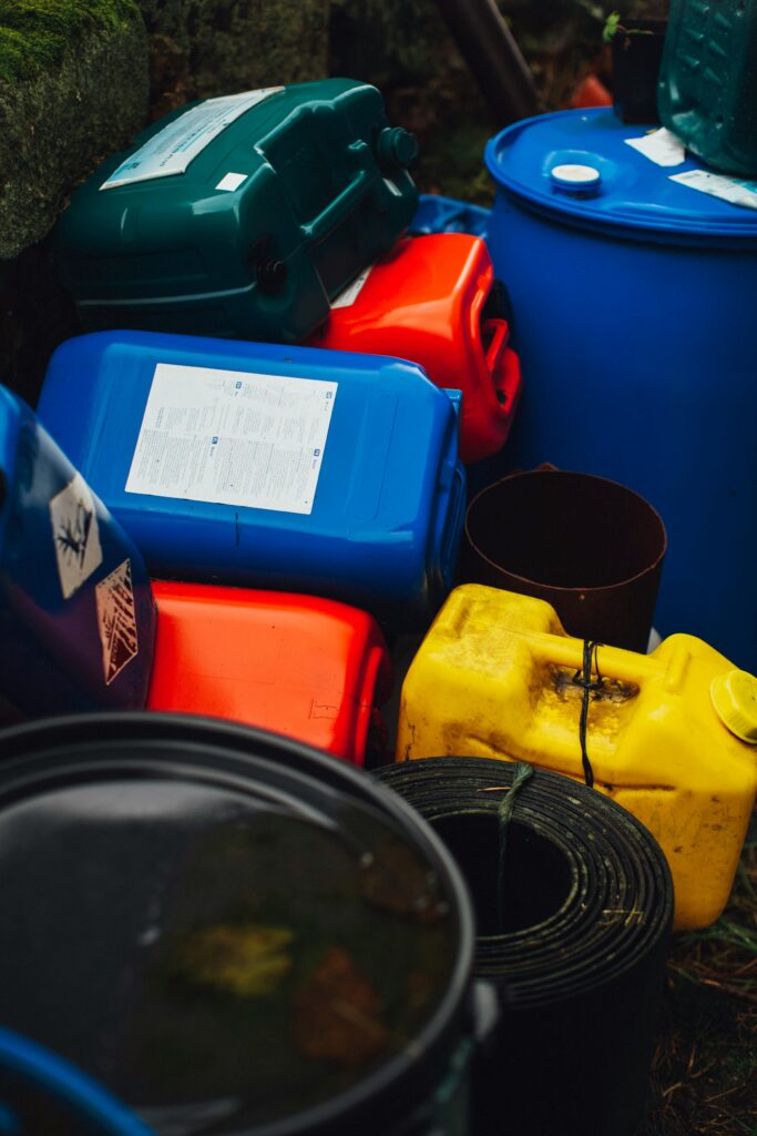 pexels-photo-3806781-3806781 Assorted colorful plastic containers and barrels stacked outdoors, showcasing waste management.
